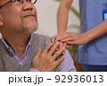 Close up hand of hands of nursing aide holding and patting winkled hand of a patient.Domiciliary care for sick elderly. 92936013