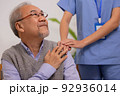 Close up hand of hands of nursing aide holding and patting winkled hand of a patient.Domiciliary care for sick elderly. 92936014