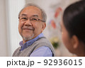 Happiness Cheerful elderly men talking with female caregiver nurse doctor having health checking consult at home. 92936015