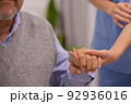 Close up hand of hands of nursing aide holding and patting winkled hand of a patient.Domiciliary care for sick elderly. 92936016