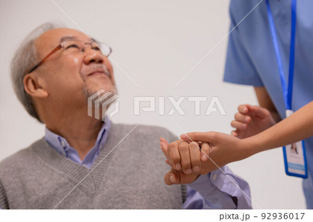 Close up hand of hands of nursing aide holding and patting winkled hand of a patient.Domiciliary care for sick elderly. 92936017