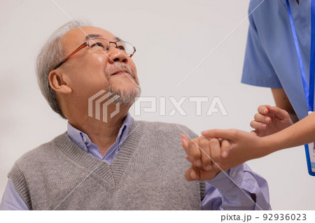 Nursing aide holding and patting winkled hand of a patient.Domiciliary care for sick elderly. 92936023