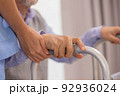 Close up.Asian nurse holding an elderly man with a walking stick for physiotherapy. 92936024