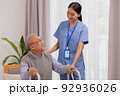 Asian nurse holding an elderly man with a walking stick for physiotherapy. 92936026