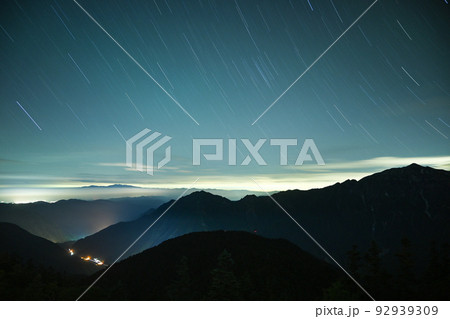 8月の晴天の下、西穂高岳稜線から岐阜県の夜景と北アルプスを眺める　軌跡で見る星空 92939309