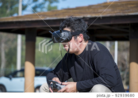 一人称視点で鳥になったような映像を撮影できるFPVドローンを操縦する男性 92939680