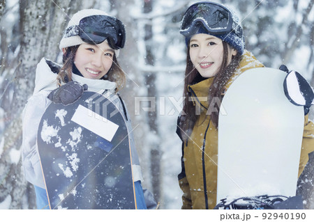 雪の降るスキー場でポーズをするスノボ女子　女子旅 92940190