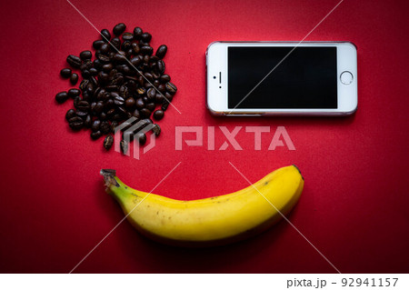 【日本】赤い背景の上に置かれたスマートフォン・バナナ・コーヒー豆 92941157