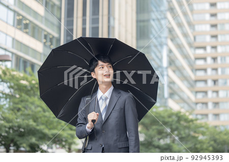 ビジネス　スーツ姿で日傘をさす男性 92945393