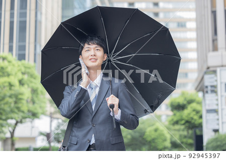 ビジネス　スーツ姿で日傘をさす男性 92945397
