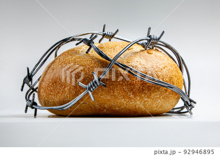 A loaf of round wheat bread wrapped with barbed wire. The concept of food crisis, food shortage 92946895