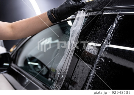 employee of the car detailing studio protects the car body with a protective film employee of the car detailing studio protects the car body with a protective film 92948585