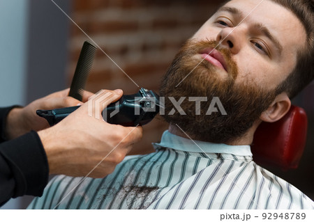 Barber master cuts beard to a brutal guy. Barber master cuts beard to a brutal guy. 92948789