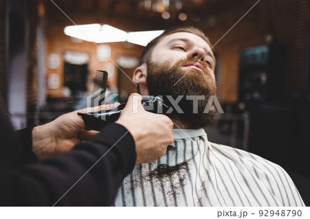 Barber cuts beard to a brutal guy. Barber cuts beard to a brutal guy. 92948790