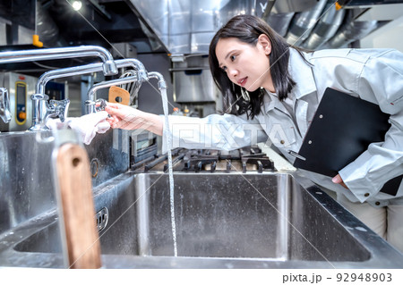 厨房を確認する若い女性　業務用ステンレスシンク　業務用流し台　 92948903