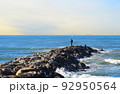 Fisherman on Masonry breakwater. A fisherman catches fish in the sea on a stone breakwater. 92950564