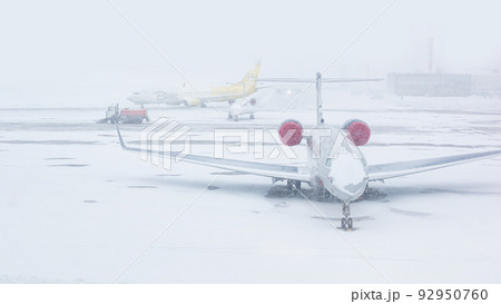 Snow covered commercial plane at the airport. Close-up of the plane after snowfall. Winter bad weather conditions. Snow covered commercial plane at the airport. Close-up of the plane after snowfall. Winter bad weather conditions. 92950760