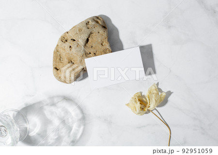 Still life scene with glasses on marble background in sunlight and blank business, greeting card, invitation mockup. Long harsh shadows.  92951059