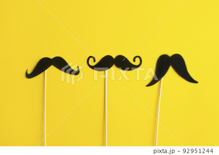 Father's Day Holiday Concept. Transparent glasses, stylish black paper photo booth props moustaches on yellow background.  92951244