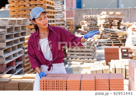 Female builder standing amongst brick stacks outdoors Female builder standing amongst brick stacks outdoors 92951443