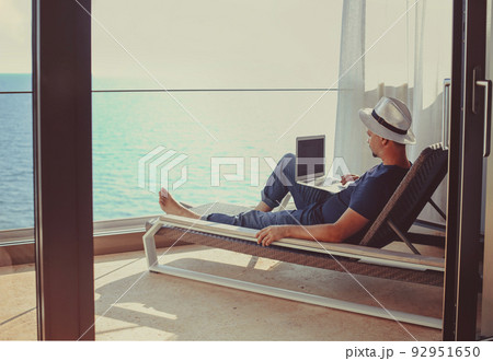 Relaxed young man at home on the balcony. Holiday and travel concept Relaxed young man at home on the balcony. Holiday and travel concept 92951650