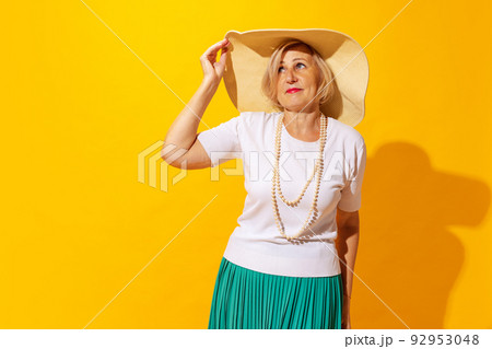 Sad mood. Elegant senior woman in summer style outfit and hat isolated on bright yellow background. Concept of beauty, emotions, vacation, travel 92953048
