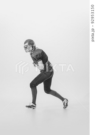 Portrait of concentrated young man, american football player in motion, action. Black and white photography. Centre-back Portrait of concentrated young man, american football player in motion, action. Black and white photography. Centre-back 92953150