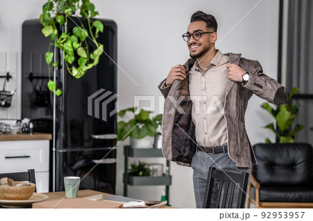 Man putting on jacket standing near table Man putting on jacket standing near table 92953957