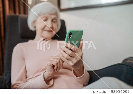 Elderly lady in beige blouse with a smartphone in hand 92954005