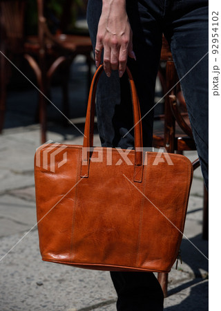 close-up photo of orange leather bag in a woman's hand 92954102