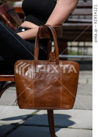close-up photo of brown leather bag on a wooden chair close-up photo of brown leather bag on a wooden chair 92954121