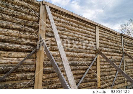traditional wooden house peeled log wall during cobntruction process with diagonal props traditional wooden house peeled log wall during cobntruction process with diagonal props 92954429
