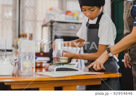 Young boy measuring ingredient for baking in kitchen. 92954646