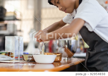 Happy boy cracking an egg for baking a cake in kitchen. Happy boy cracking an egg for baking a cake in kitchen. 92954650