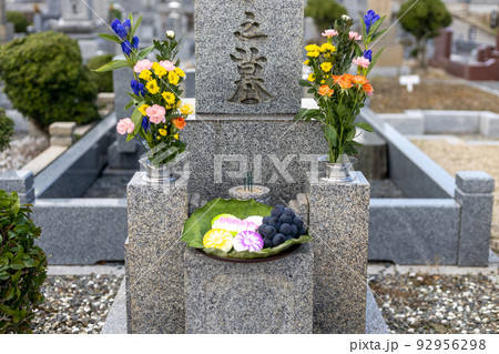 きれいなお花とお菓子とブドウがお供えしてあるお墓 92956298