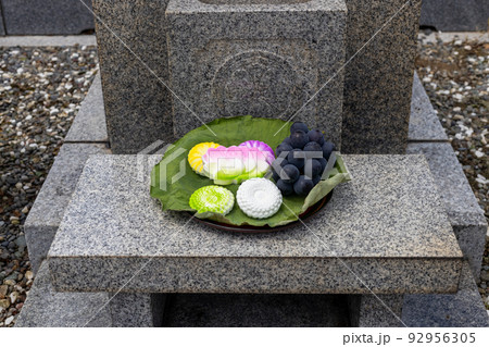 お菓子とブドウがお供えしてあるお墓 92956305
