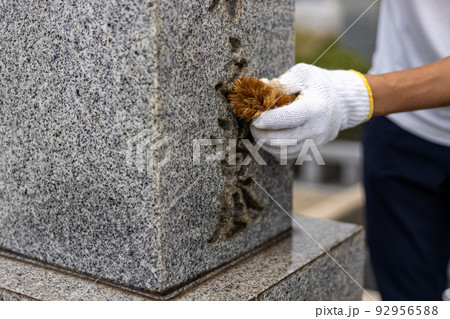 お墓参りに来てお墓の掃除をしている男性 92956588