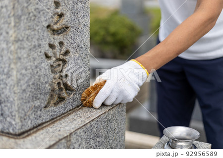 お墓参りに来てお墓の掃除をしている男性 92956589