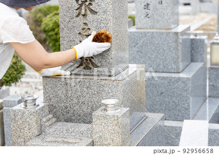 お墓参りに来てたわしでお墓の掃除をしている女性 92956658
