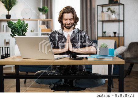 Bearded male freelance meditating with closed eyes. Bearded male freelance meditating with closed eyes. 92958773