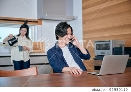 テレワーク中に電話する男性とコーヒーを飲む女性 テレワーク中に電話する男性とコーヒーを飲む女性 92959119