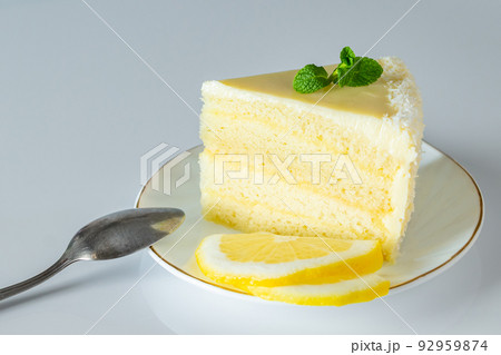 Piece of biscuit dessert with lemon and coconut flakes. Layered vanilla cake on white plate. Piece of biscuit dessert with lemon and coconut flakes. Layered vanilla cake on white plate. 92959874