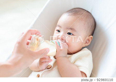 哺乳瓶に手を添える赤ちゃん　自分で持つ　セルフ飲み 92960110