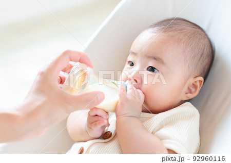 哺乳瓶に手を添える赤ちゃん　自分で持つ　セルフ飲み 92960116