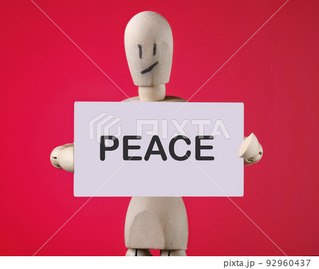 The actual PEACE inscription on the card is in the hands of a wooden man 92960437