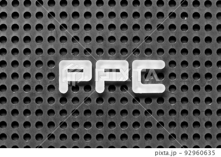 White alphabet letter in word PPC (Abbreviation of pay per click) on black pegboard background 92960635