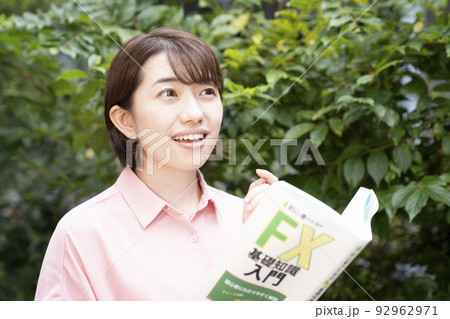 投資の本を笑顔で読む女性 投資の本を笑顔で読む女性 92962971