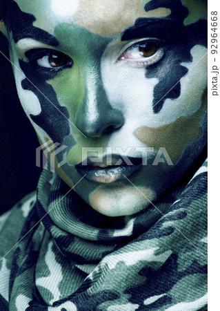 Beautiful young fashion woman with military style clothing and face paint make-up, khaki colors, halloween celebration closeup 92964668