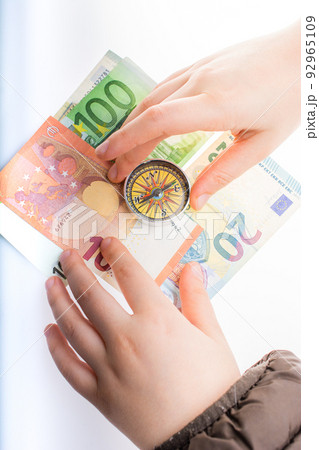 Hand holding compass on Euro banknotes as business, finance concept Hand holding compass on Euro banknotes as business, finance concept 92965109
