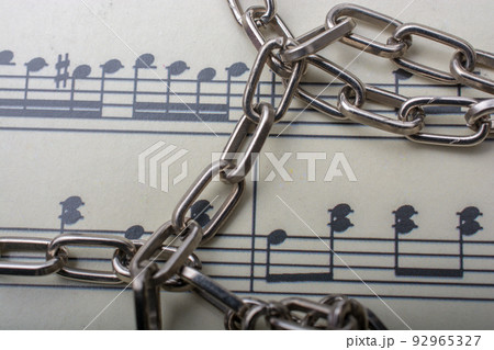 Metal chain placed on paper with musical notes 92965327